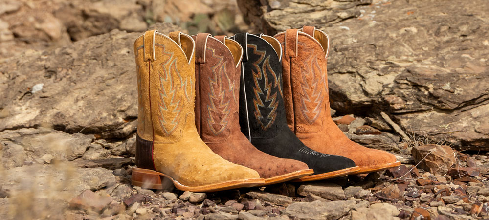Una colecci&oacute;n de botas vaqueras Justin CPX sobre grava.