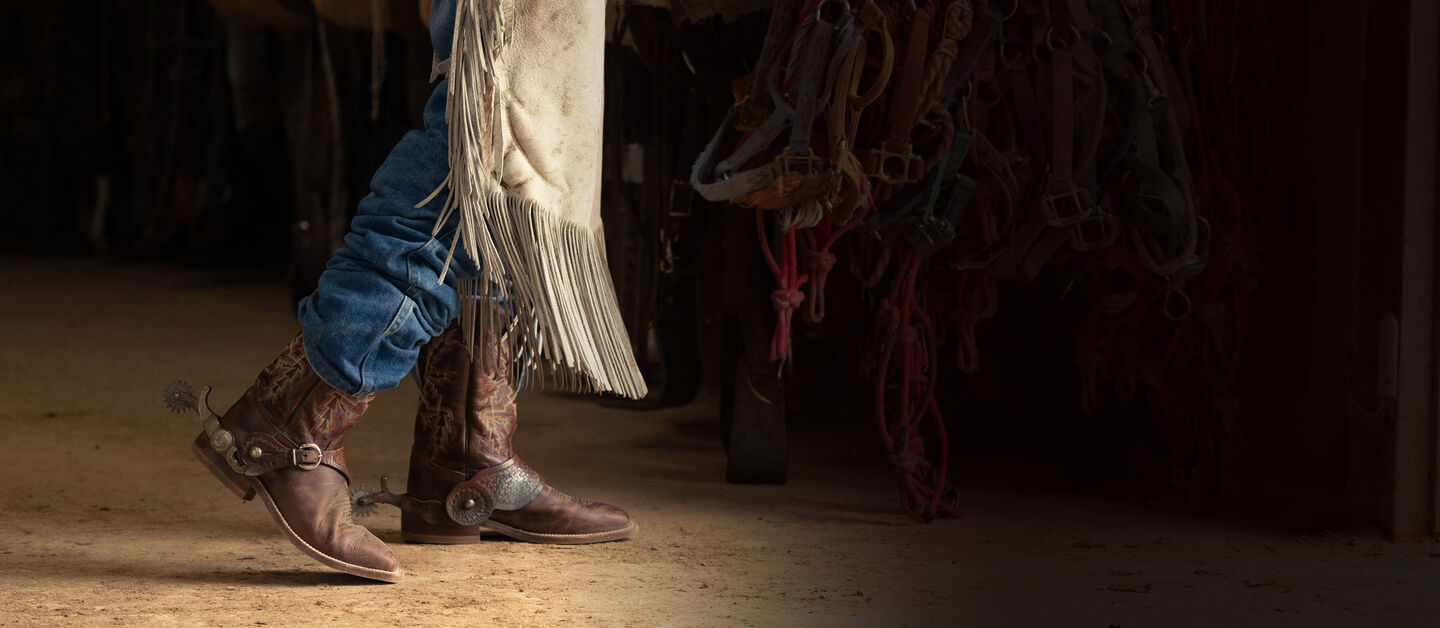 A Man wearing the bender in dark brown walking in a barn.