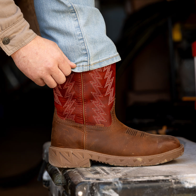 A man wearing the Markout 11" Steel Toe boot in red and brown.