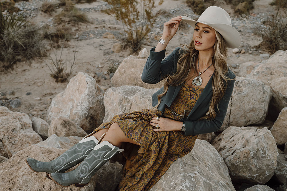 A woman wearing the Justin Verlie 17&rdquo; Western Boot in dusty blue.