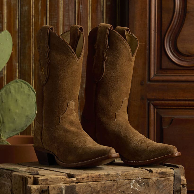 The Fancy 11" Suede western boot in Mocha (brown)on a box made of wood.