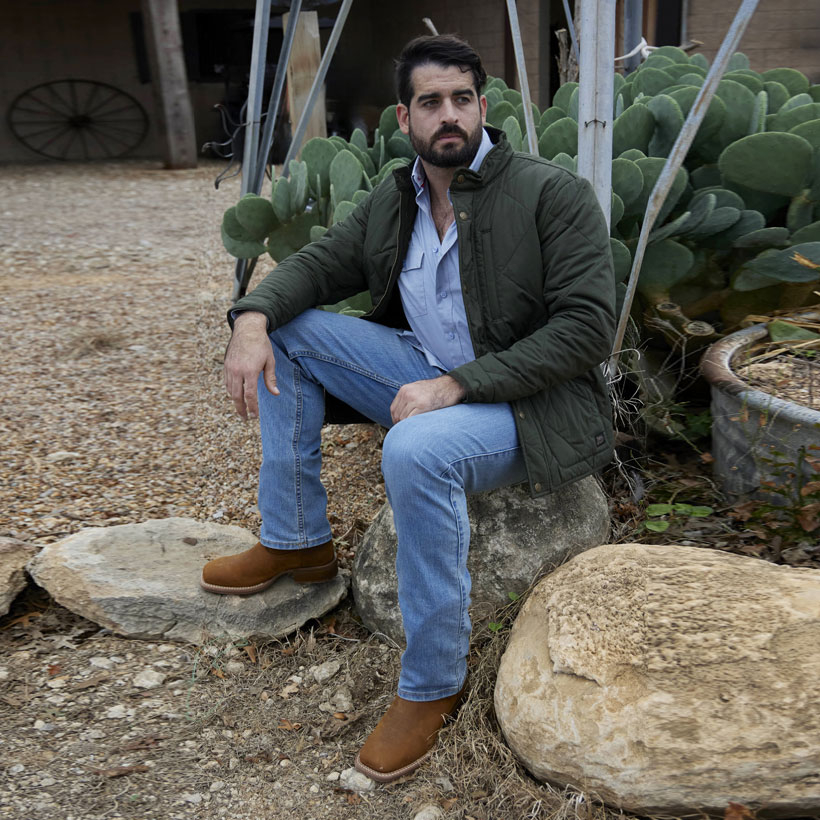 A man wearing the Justin Quilted Jacket in Olive and 1879 Straight Leg Mens Jeans in light wash.