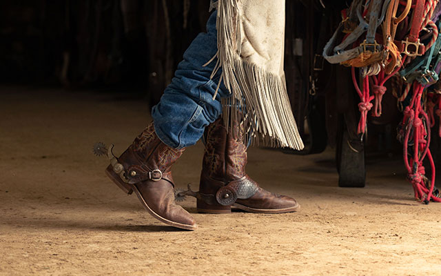 A Man wearing the bender in dark brown walking in a barn.