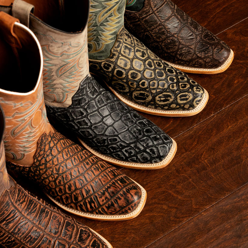 The Mcneely 13" Crocodile Western boots in Tumbled brown, Taupe(tan), Rustic Brown, Graphite Grey, and Cocoa Brown on a wood floor.