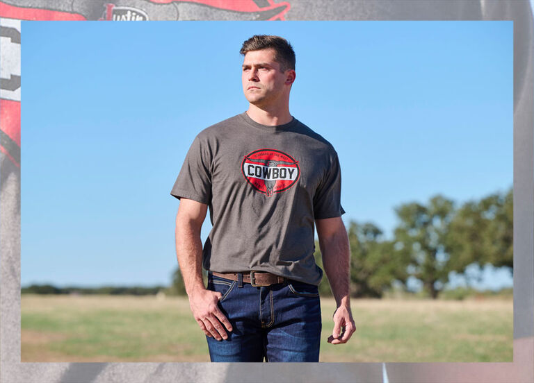 A Man standing in a field wearing a Justin Cowboy graphic t-shirt.