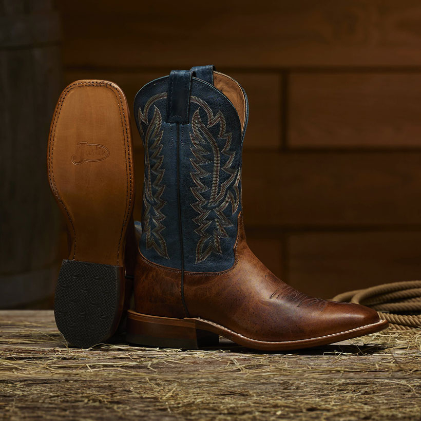 The Poston 11" Western boots in Amber Brown on the floor of a barn.