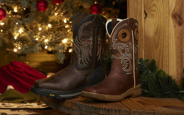 Two pairs of men's work boots sitting on a spool in front of a Christmas scene. 