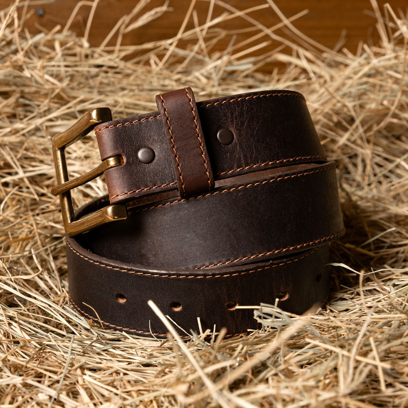 The Justin Bomber Belt in Brown laying in a pile of hay.