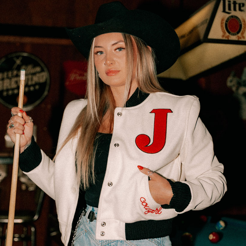 A woman wearing the Women's Varsity Jacket in white and black.