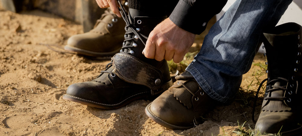 Un hombre prob&aacute;ndose las botas Drennan 7" Lace-Up Roper en color caqui (marr&oacute;n).