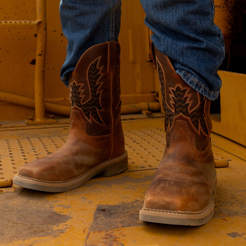 Un hombre que lleva puestas las botas de trabajo impermeables Bolt de 11 pulgadas, en color marr&oacute;n.