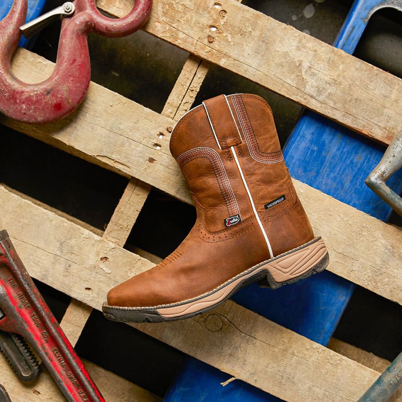 The 8" Rush Waterproof Work Boot in Cedar Brown on a wood pallet surrounded by tools.