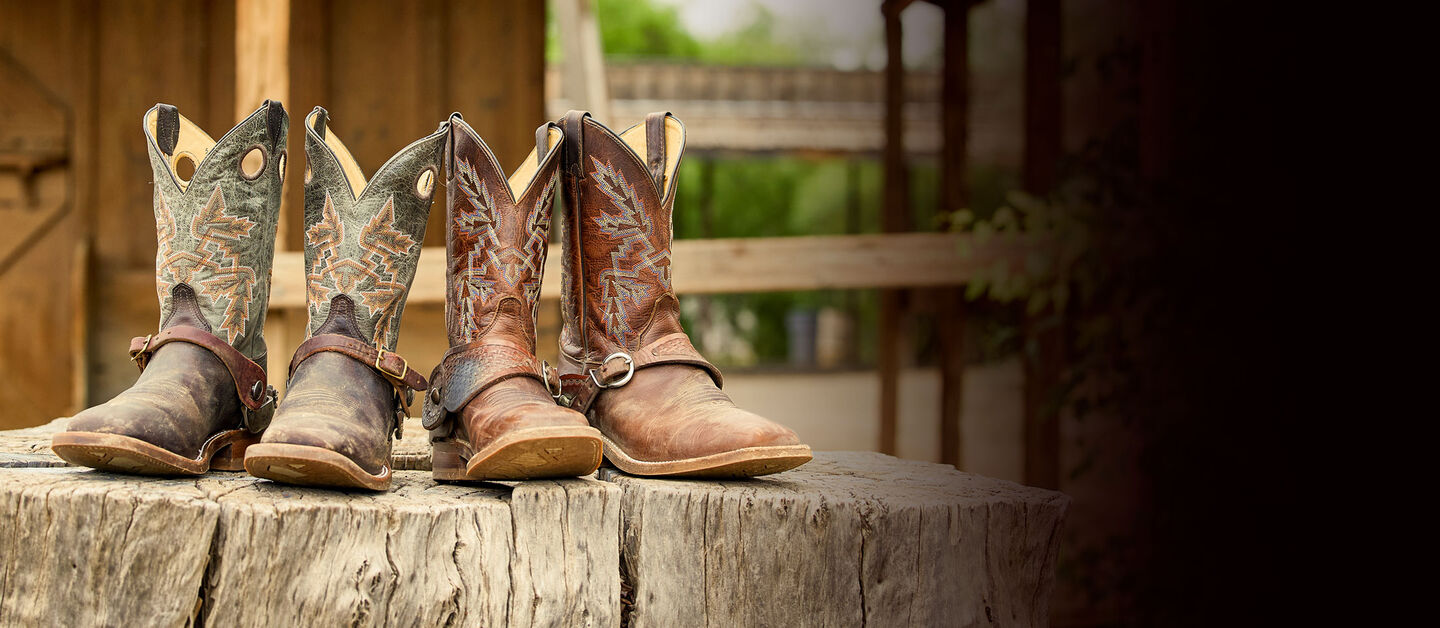 Two pairs of Bent Rail boots with spurs on posed on a log.