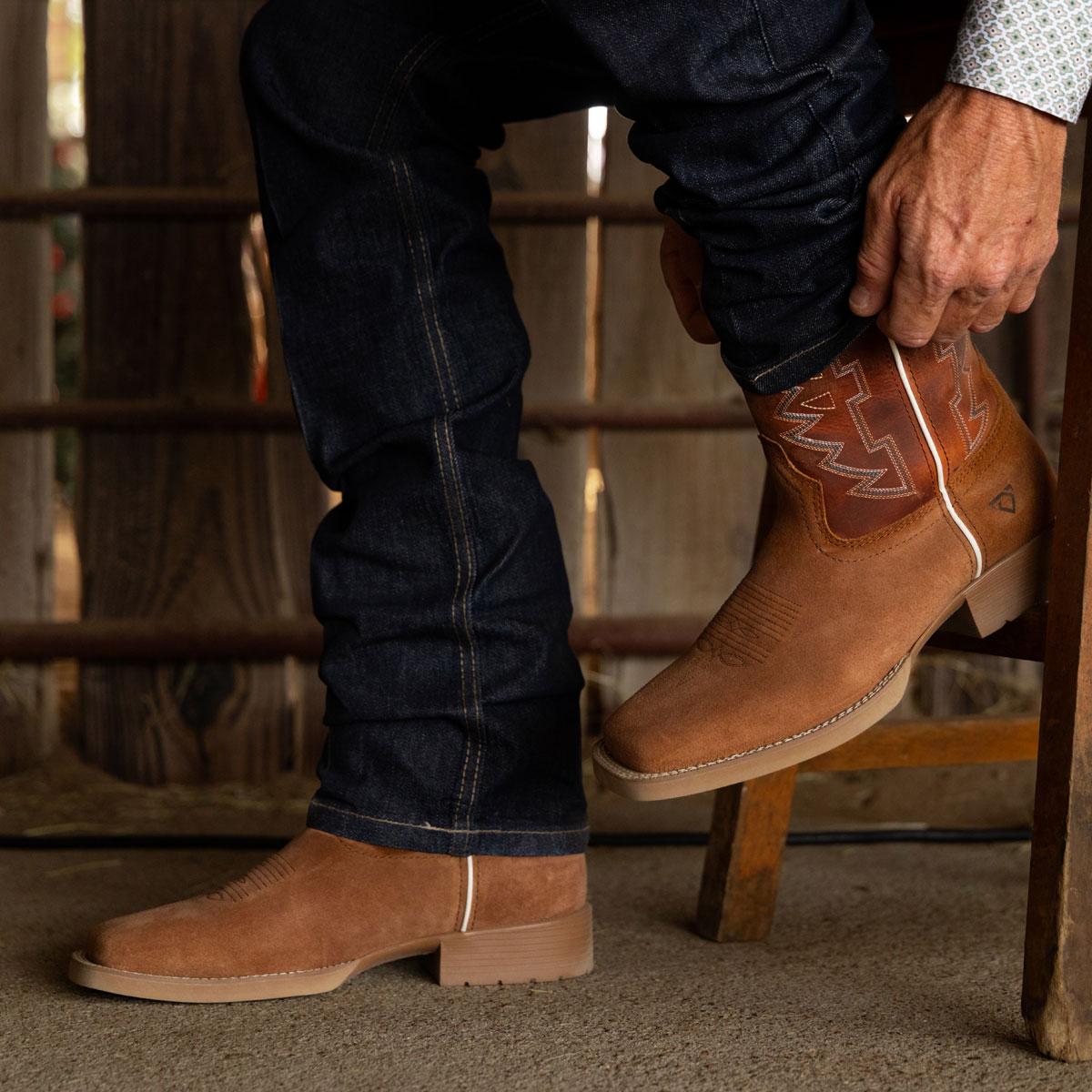 Un hombre que lleva puestas las botas vaqueras para hombre Dear Rodeo de 11 pulgadas en color &oacute;xido (marr&oacute;n). Compra este estilo.