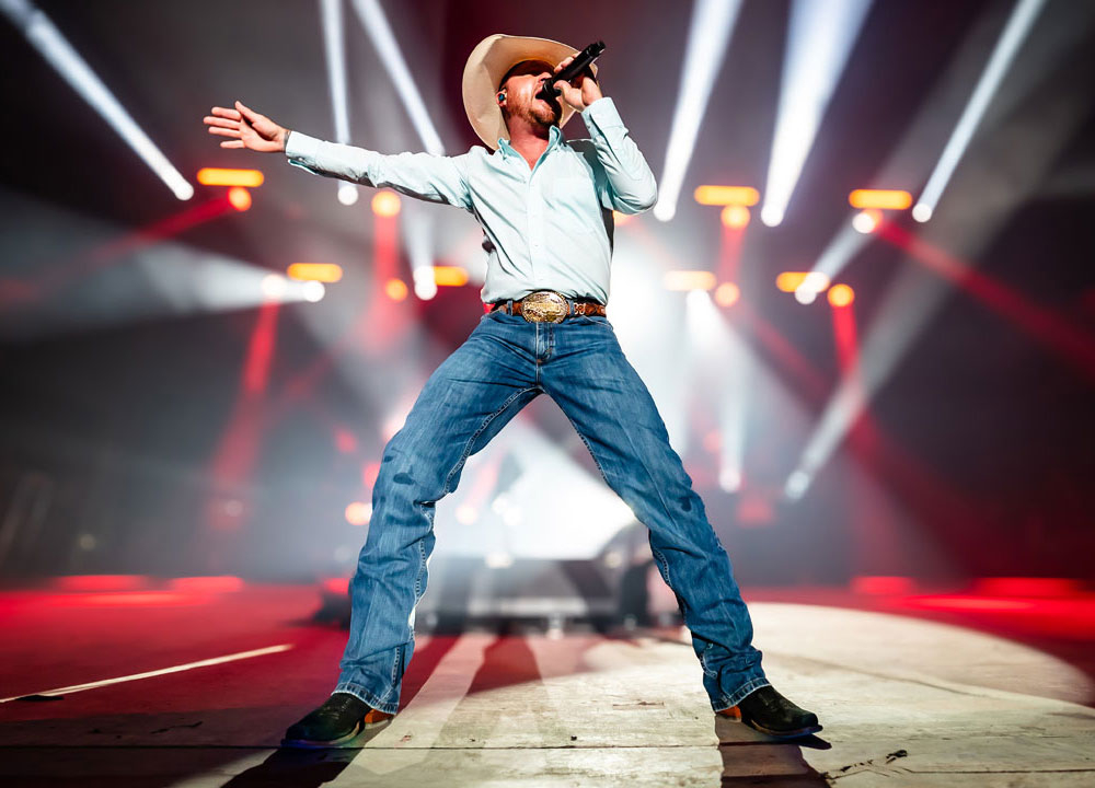 A man wearing western attire performing on stage.