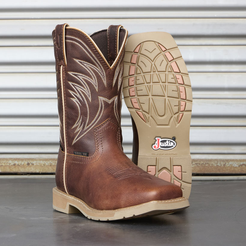 Men’s 11” steel toe Daywork Stampede work boot in pecan brown sitting on a concrete floor in front of a corrugated metal wall