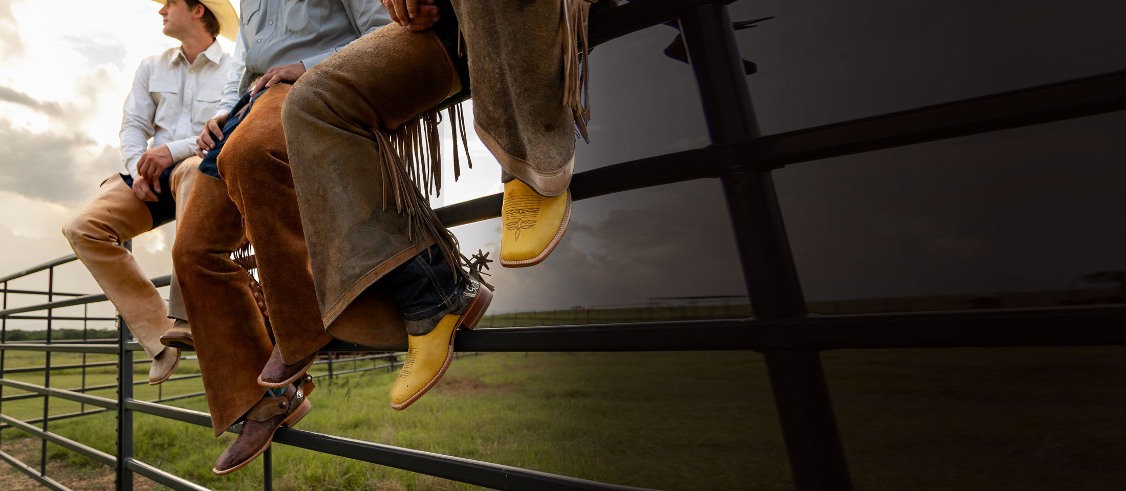 Three men sitting on a metal fence wearing Men’s CPX Western boots.