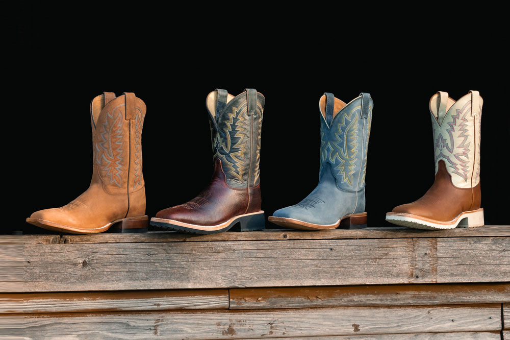 Men’s Rancho 11” Western boots in grey, Men’s Rancho 11” Western boots in brown, Trainor 11” Western boots in brown and Trainor 11” Western boots in dark brown sitting on a window sill made of wood.