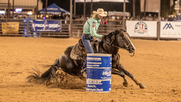 A woman barrel racing at a rodeo.