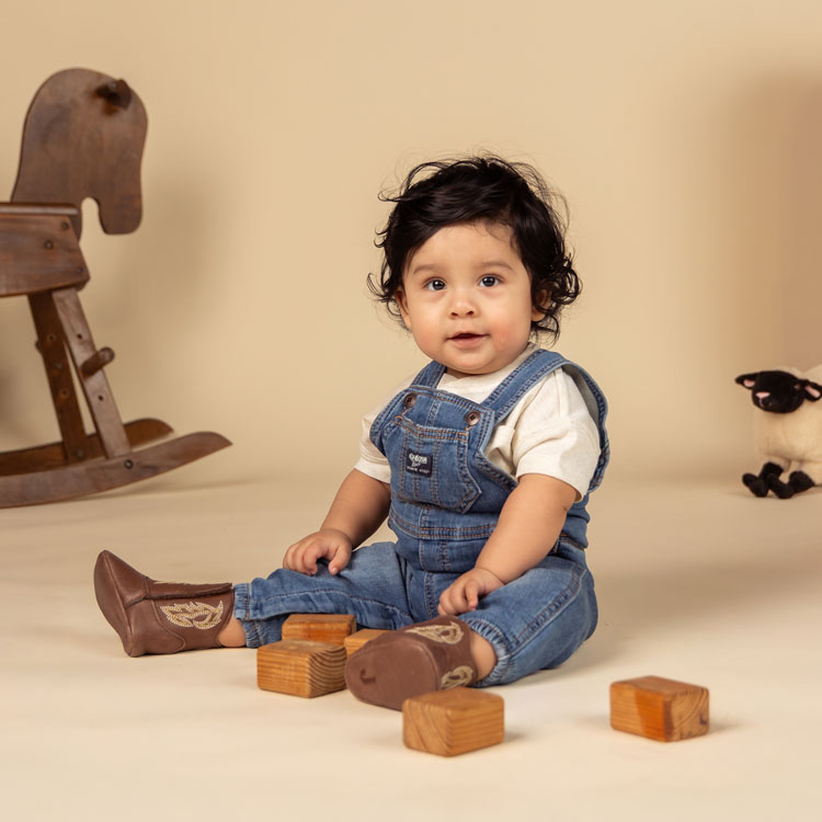 A baby wearing Baby Canter in peanut brown. Shop Baby Canter.