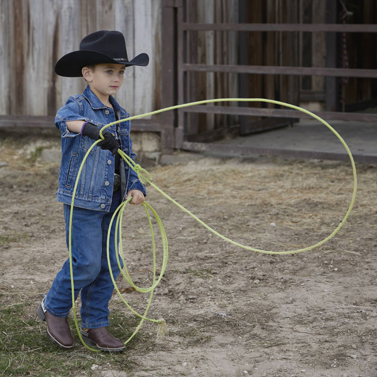 Kids’ Bowline Junior in brown with spurs, worn by a kid standing in grass.