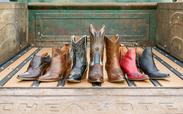 7 boots colored brown black and red in the bed of a green Chevrolet truck