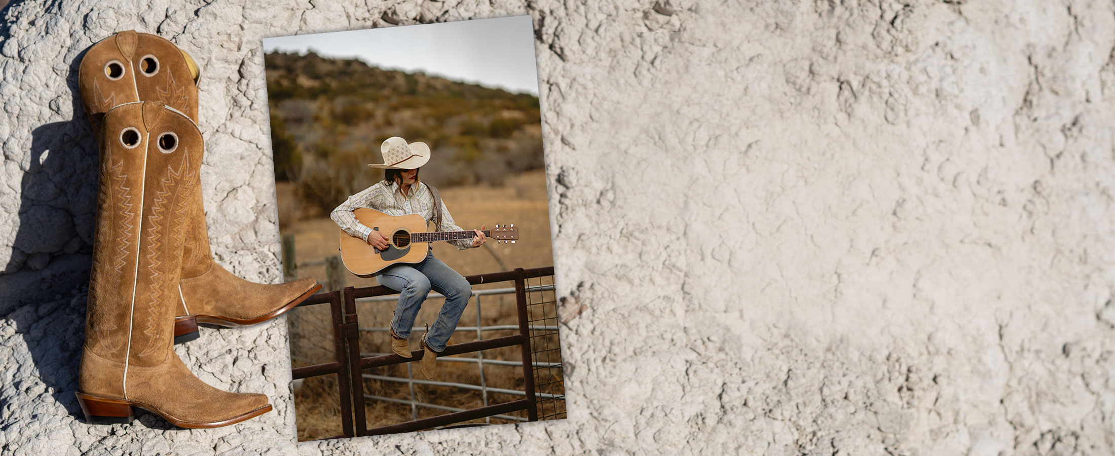 Jenna Paulette wearing the Sunrise boots in tan suede and sitting on a fence, holding her guitar. 