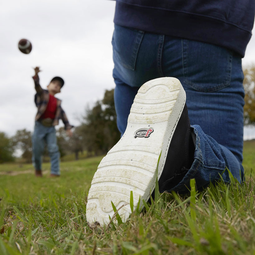 Men’s Hazer in black worn by a man kneeling down, playing football with his son and showing the outsole to the camera. 