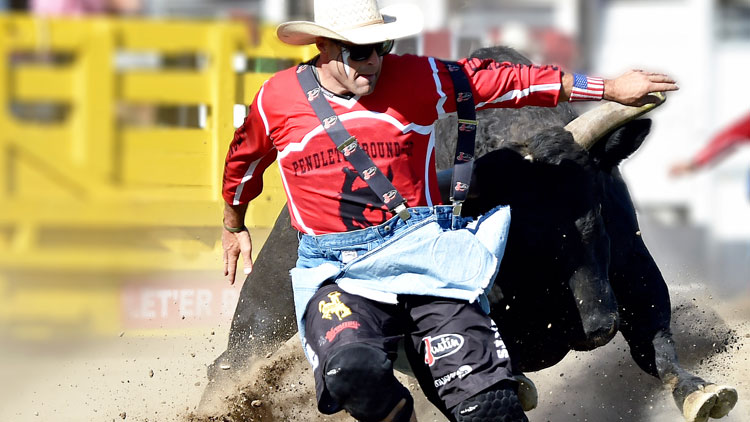 Dusty Tuckness con una camisa roja y parándose delante de un toro.
