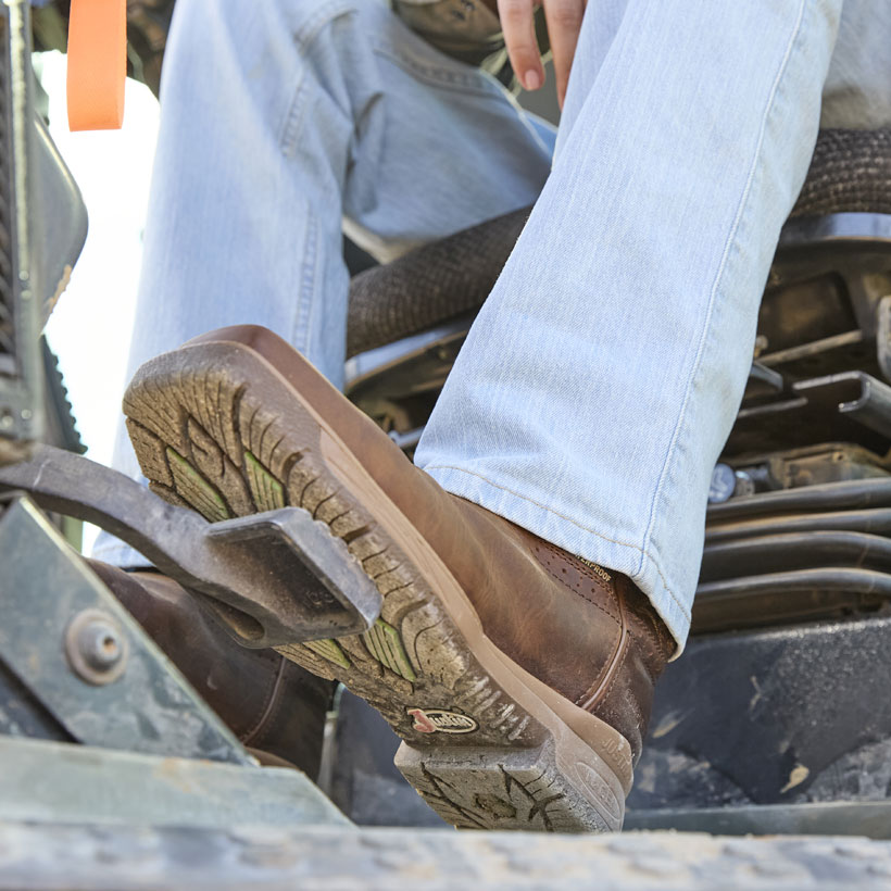 Men’s NiTread 11” waterproof nano comp toe work boots in brown worn by a man in an excavator with his foot on the pedal. 