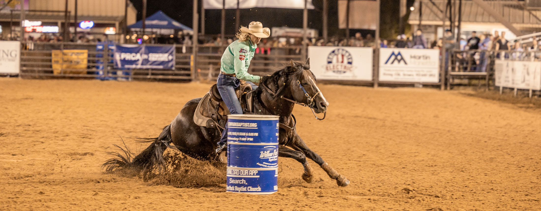 A woman barrel racing at a rodeo.