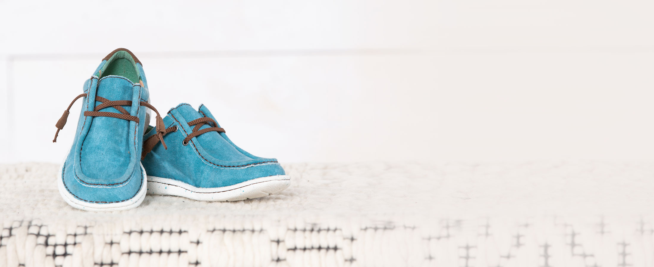 Women’s Hazer in turquoise, posed on a white blanket in studio. 