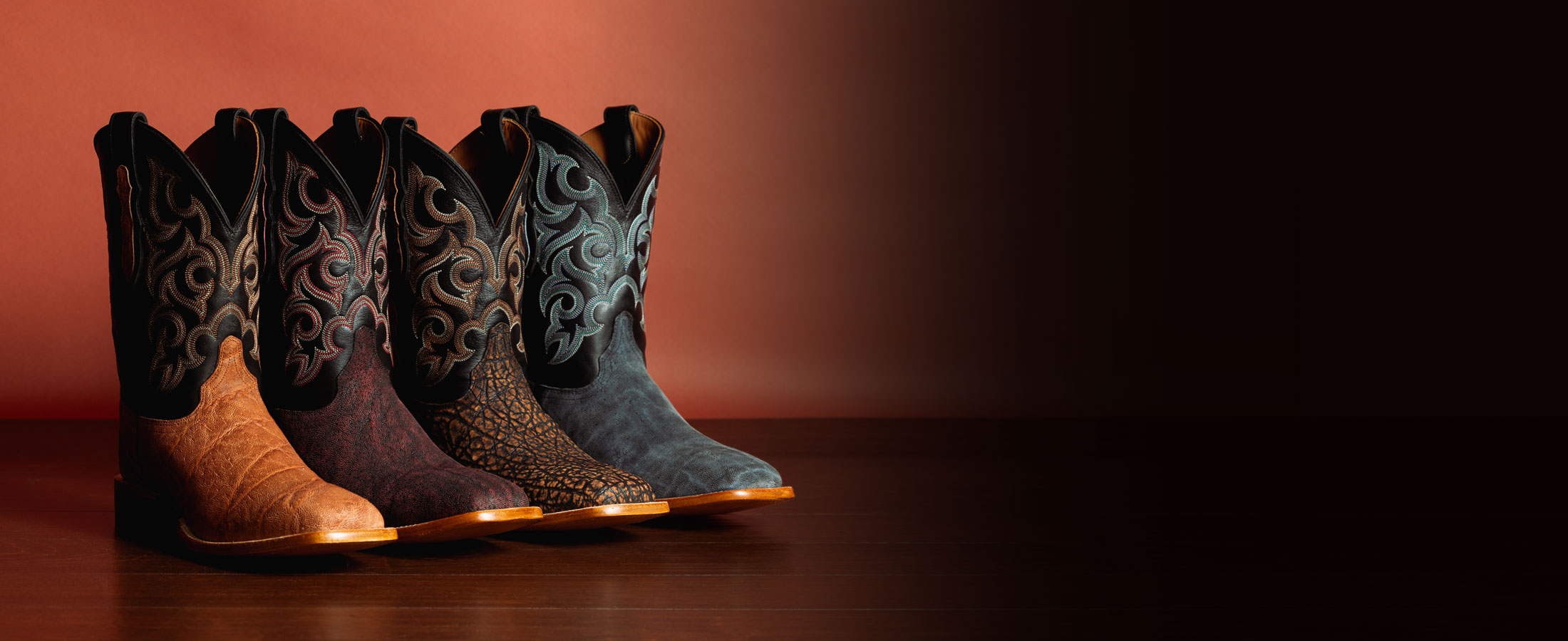 Pards Elephant western boots in Brown, Pards Elephant western boots in red, Pards Elephant western boots in tan, and Pards Elephant western boots in black, posed in front of an orange wall.