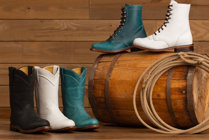 Women’s McKean 7” Lace-Up Roper boots in white, Women’s McKean 7” Lace-Up Roper boots in turquoise, Holland 10” Roper Boots in Black, Holland 10” Roper Boots in White, and Holland 10” Roper Boots in Turquoise posed on a wooden barrel with a rope in front of a wooden background.