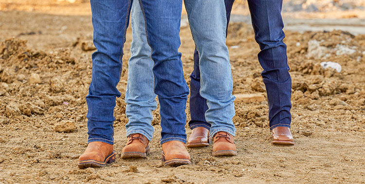Tres hombres vestidos con jeans Justin y botas Justin.