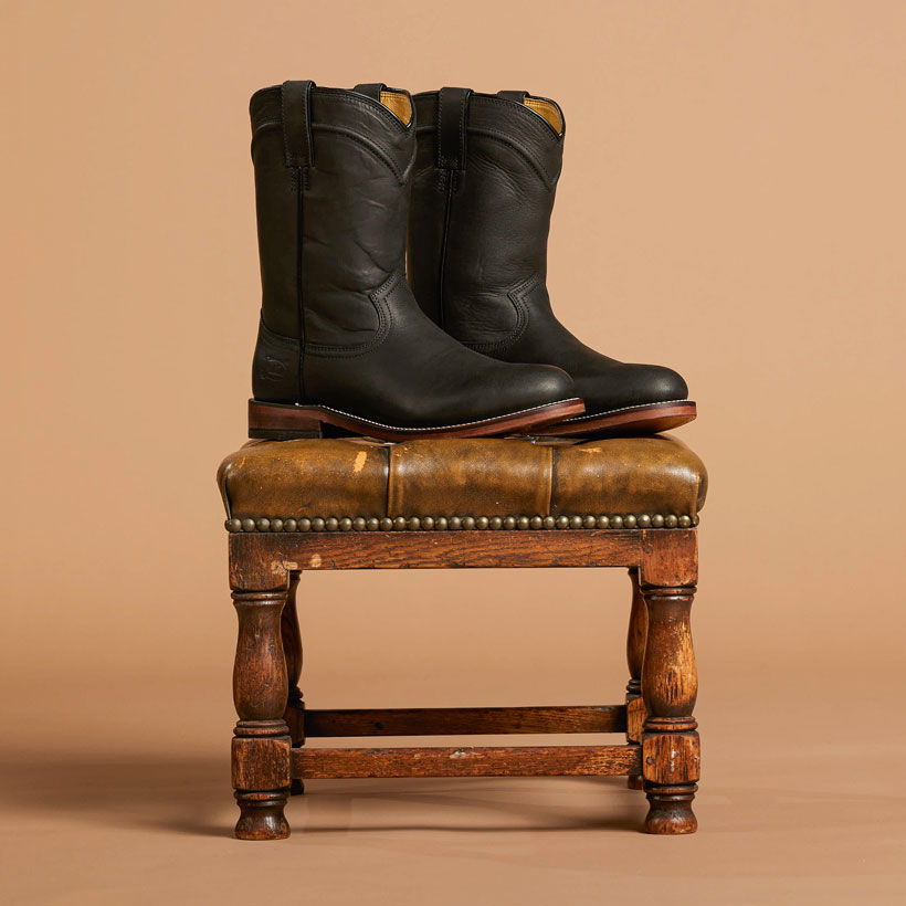 Men’s 10” Braswell roper boot in black posed on a stool. 