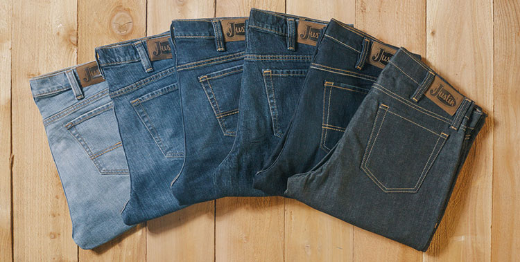 A fan of different washes of jeans ranging from light to dark denim laying on a wood background.