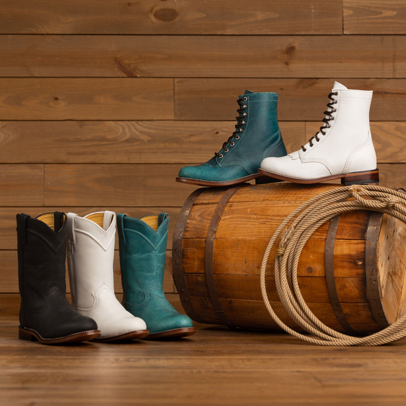 Women’s McKean 7” Lace-Up Roper boots in white, Women’s McKean 7” Lace-Up Roper boots in turquoise, Holland 10” Roper Boots in Black, Holland 10” Roper Boots in White, and Holland 10” Roper Boots in Turquoise posed on a wooden barrel with a rope in front of a wooden background.