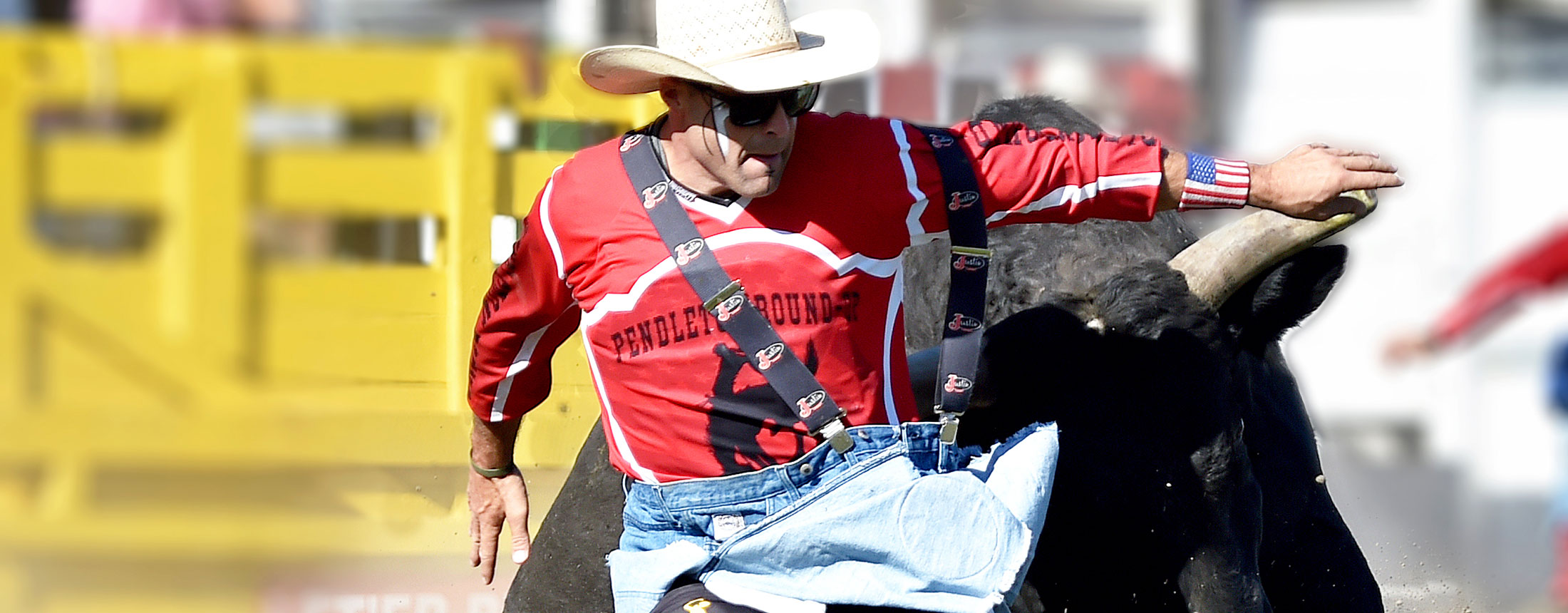 Dusty Tuckness con una camisa roja y parándose delante de un toro.