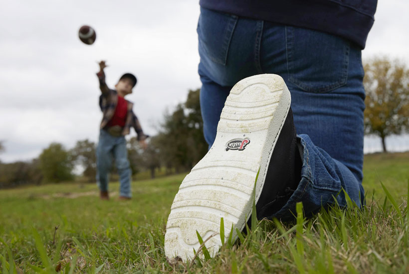 Men’s Hazer in black worn by a man kneeling down, playing football with his son and showing the outsole to the camera. 